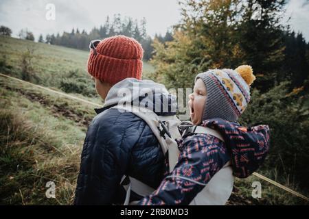 Mutter läuft in der Natur mit Tochter auf dem Rücken Stockfoto