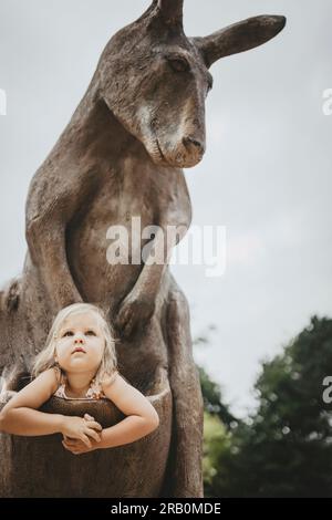 Ein Mädchen, das in der Tasche eines Holzkängurus sitzt, Dortmund Zoo Stockfoto