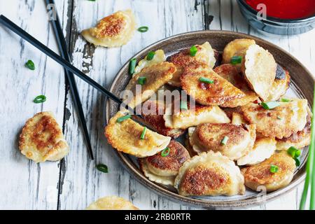 Blick von oben auf einen Teller mit goldenen gebratenen chinesischen Teigtaschen, auch bekannt als Pot Stickers, mit süßer und saurer Sauce. Stockfoto