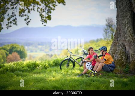 Ein Paar, Mann und Frau, die mit Fahrrädern unterwegs sind, sich ausruhen, ausruhen, Trekking, E-Bike Stockfoto