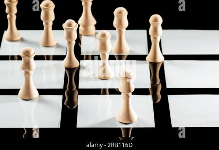 Die Schachfiguren aus Holz spiegeln sich im Glasschachbrett wunderbar wider. Stockfoto