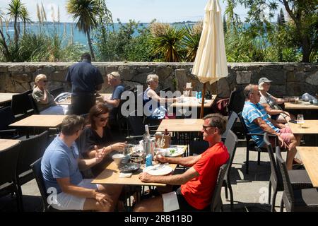 Herm, Kanalinseln, Vereinigtes Königreich. 11June 2023 Urlauber genießen ein Mittagessen vor einem Herm Island Restaurant, Blick auf Guernsey eine andere Kanalinsel. Stockfoto
