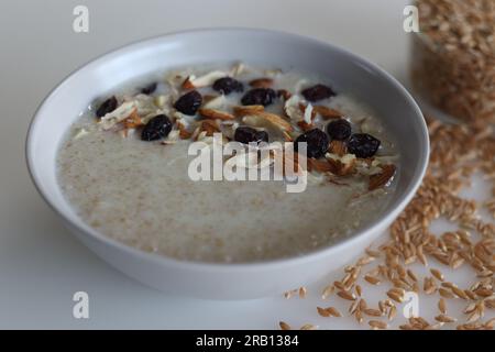 Khapli-Weizenbrei. Gesunder Haferbrei aus gebrochenem Emerweizen, in Milch gekocht und serviert mit Mandelscheiben und Rosinen. Eine Version von Haferbrei Stockfoto