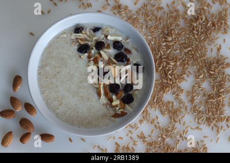 Khapli-Weizenbrei. Gesunder Haferbrei aus gebrochenem Emerweizen, in Milch gekocht und serviert mit Mandelscheiben und Rosinen. Eine Version von Haferbrei Stockfoto