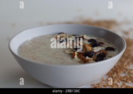 Khapli-Weizenbrei. Gesunder Haferbrei aus gebrochenem Emerweizen, in Milch gekocht und serviert mit Mandelscheiben und Rosinen. Eine Version von Haferbrei Stockfoto