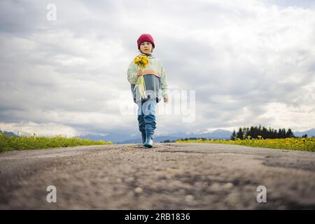 Ein Junge mit Blumenstrauß läuft auf einer unbefestigten Straße Stockfoto