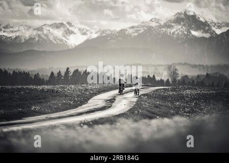 Geschwister mit Fahrrad auf einer unbefestigten Straße in den Alpen Stockfoto