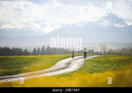 Geschwister mit Fahrrad auf einer unbefestigten Straße in den Alpen Stockfoto