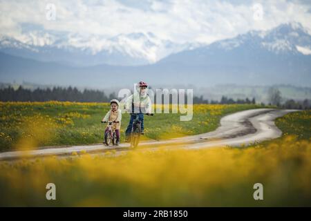 Geschwister mit Fahrrad auf einer unbefestigten Straße in den Alpen Stockfoto