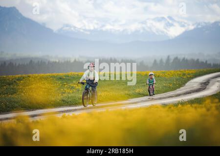 Geschwister mit Fahrrad auf einer unbefestigten Straße in den Alpen Stockfoto