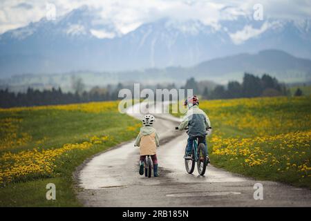 Geschwister mit Fahrrad auf einer unbefestigten Straße in den Alpen Stockfoto