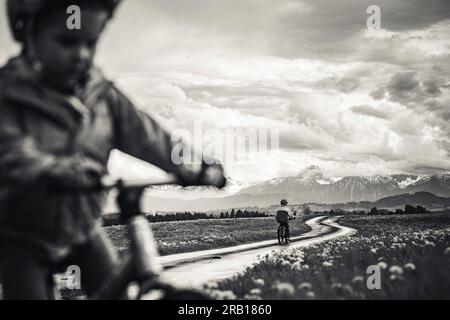 Geschwister mit Fahrrad auf einer unbefestigten Straße in den Alpen Stockfoto