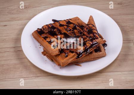 Schokoladenwaffel auf weißem Teller auf Holzhintergrund Stockfoto