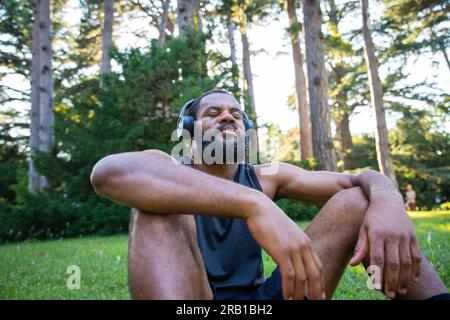 Ein Sportler entspannt sich nach einem Workout und hört Musik, atmet die frische Luft mit geschlossenen Augen. Stockfoto