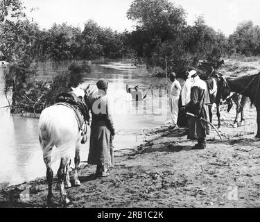 Jordanien: c. 1926 Ein Mann wird in einem Fluss in Jordanien getauft, während andere Araber am Ufer des Flusses warten. Stockfoto