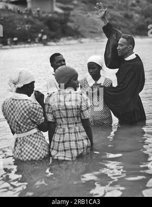 Austin, Texas: Am 2. Juni 1938 betet Ein Prediger und bereitet sich darauf vor, ein junges Mädchen unter Wasser zu setzen, während zwei andere nervös auf ihre Taufe im Colorado River warten. Stockfoto