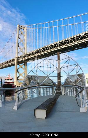 Bogenskulptur auf einer Aussichtsplattform für schwimmende Feuerwache 35 mit Feuerwehrboot St. Francis und Bay Bridge Embarcadero San Francisco Kalifornien USA Stockfoto