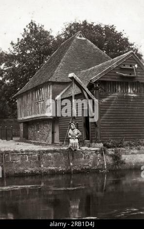Fordwich, England: ca. 1900 Eine Frau dämonisiert den "Ducking Stool", der im späteren Mittelalter und Mittelalter in England hauptsächlich für schimpfende Ehefrauen und andere soziale Verfehlungen verwendet wurde. Stockfoto