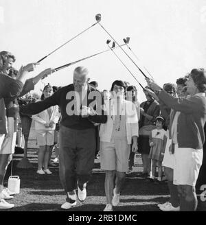 Oceanside, Kalifornien: ca. 1957 Ein glücklicher Mann und eine glückliche Frau gehen Hand in Hand durch zwei Reihen von Frauen mit einem Bogen von Golfschlägern. Stockfoto