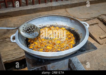 Eine Pfanne gebratenes Kelewele mit einer Kelle in einer Straße Afrikas Stockfoto