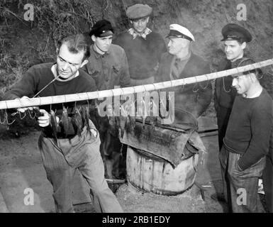 San Francisco, Kalifornien: 30. Januar 1940 Besatzungsmitglieder des deutschen Streuners Columbus verbringen ihre Zeit beim Angeln, während sie an der Angel Island Immigration Station interniert sind. Die Fische werden geräuchert, um sie als Snacks zu essen. Die Crew wartet auf den Transport zurück nach Deutschland. Stockfoto