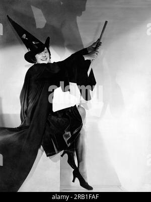 USA: c. 1930 Eine junge Frau mit einem Besen in einem Hexenkostüm an Halloween. Stockfoto