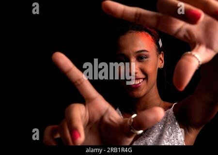 Studio-Porträt eines hübschen Teenagers, das Handgesten vor der Kamera macht. Isoliert auf schwarzem Hintergrund. Stockfoto