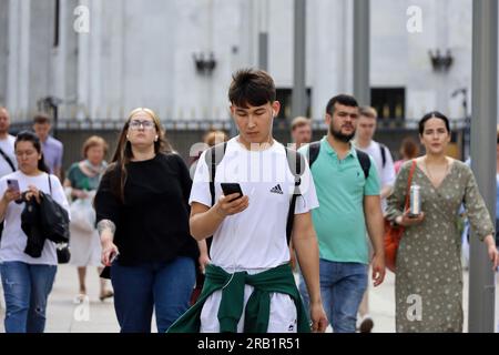 Ein Asiate mit Handy, der im Sommer auf der Straße rumläuft Stockfoto