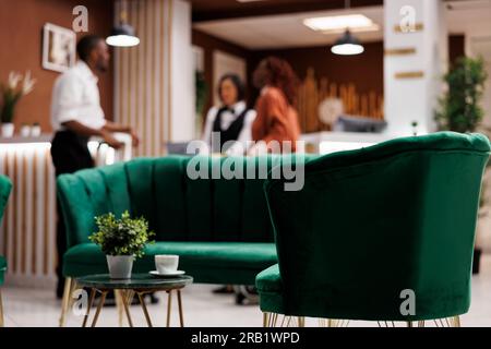 Lounge-Bereich in der luxuriösen Hotellobby mit Sofa, das für Gäste genutzt wird, um auf den Check-in und die Registrierung zu warten. Geräumiger Resorteingang mit Marmorböden und Rezeption, einladende Menschen. Stockfoto