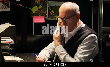 Privatdetektiv sammelt Informationen aus dem Festnetz, macht Notizen über die Hintergrundüberprüfung des Verdächtigen. Ein Mann, der in einem Straffall ermittelt, Polizeibehörde. Stockfoto