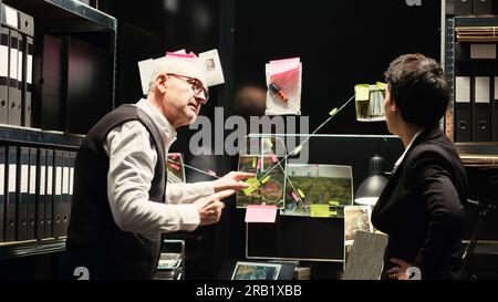 Experten verbinden Hinweise an Bord, analysieren forensische Beweise und Beweise, um kriminelle Aktivitäten zu lösen. Team von Beamten, die Ermittlungen mit Verschlusssachen durchführen. Stativaufnahme. Stockfoto