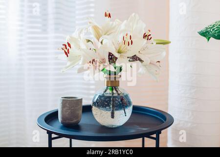 Nahaufnahme des Sommerstraußes mit Rosenblumen in durchsichtiger Vase auf Tisch für Fenster. Gemütliche Einrichtung und Dekor zu Hause. Leerzeichen Stockfoto