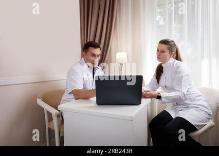 Zwei Ärzte, Mann und Frau, die sich unterhalten und auf den Computerbildschirm schauen Stockfoto