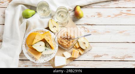 Leckere Birnenmarmelade mit verschiedenen Käsesorten und Wein auf Weiß Holzhintergrund Stockfoto