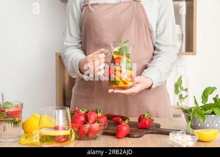 Eine Frau, die Limonade mit Erdbeere und Zitrone in der Küche hält Stockfoto