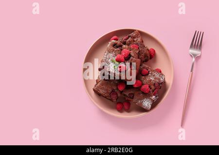 Teller mit Himbeer-Schokoladen-Brownie auf pinkfarbenem Hintergrund Stockfoto