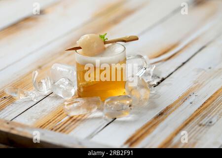 Iced Lychee Tea on Mini Glass, über Holztisch. Frisches Tropisches Sommergetränk Stockfoto