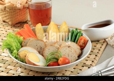 Hähnchen Galantine mit verschiedenen gedämpften Gemüsesorten, serviert mit Pilzsauce. Bekannt als Selat Solo Galantin Ayam Stockfoto