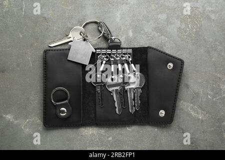 Eleganter Lederhalter mit Tasten auf grauem strukturiertem Tisch, Draufsicht Stockfoto