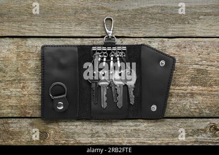 Lederhalter mit Schlüssel auf altem Holztisch öffnen, Draufsicht Stockfoto