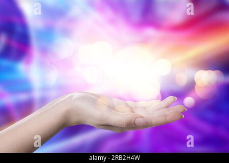 Aura-Phänomene. Frau mit Energielichtern, die aus ihrer Hand vor farbigem Hintergrund kommen, Nahaufnahme Stockfoto