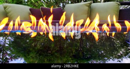 Glaskamin neben Terrassenmöbeln und mit einer Baumreflektierung auf dem Glas Stockfoto