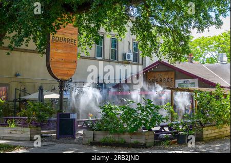 NEW ORLEANS, LA, USA - 5. JULI 2023: Bourrée Cajun Smokehouse mit Wassernebelsystem, das an einem heißen Tag im Außenbereich sprüht Stockfoto