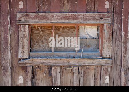 Nahaufnahme einer isolierten Scheune oder Hütte mit verwittertem Holz zeigt Flecken, Abdeckungen und Rahmen. Zusätzliche Holzrahmen hinzugefügt. Glas fehlt. Stockfoto