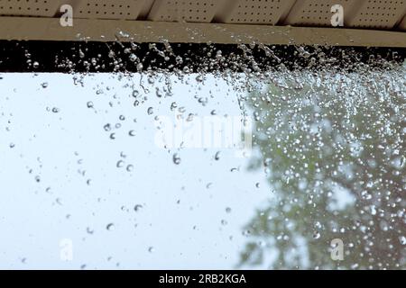 Wenn es stark regnet, fließt Wasser aus der Dachrinne. Stockfoto