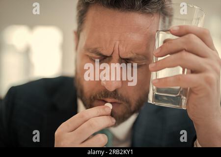 Müder Mann fühlt Schmerzen beim Brillenhalten trockene gereizte Augen ermüdet von Computerarbeit, gestresster Mann leidet an Kopfschmerzen. Mann nimmt Medizin Stockfoto