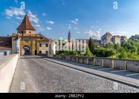 Cesky Krumlov gelbes Stadtmauertor mit Brücke über den Wassergraben, unterhalb der gotischen Burg Stockfoto