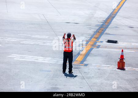 Ein Marshaller von Unifi Aviation Services leitet ein Flugzeug auf eine Parkposition am Myrtle Beach International Airport in Myrtle Beach, SC, USA. Stockfoto