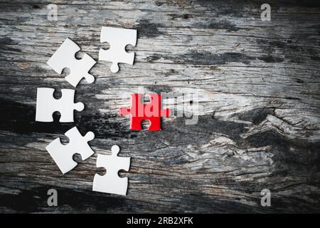 Weiße Details des Puzzlestücks auf Holzhintergrund. Konzept der Zusammenarbeit als Business-Team. Die Idee, sich einzubringen, für s zu arbeiten Stockfoto