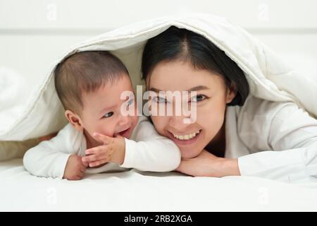 Glückliche Mutter und Baby liegen liegend in der Decke auf einem Bett Stockfoto